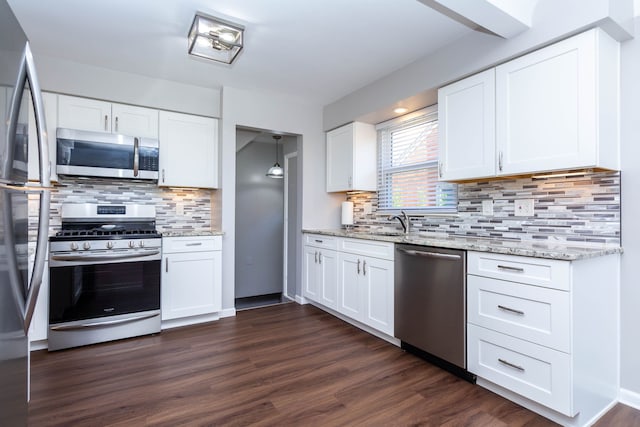 kitchen with appliances with stainless steel finishes, backsplash, dark wood-type flooring, and light stone counters
