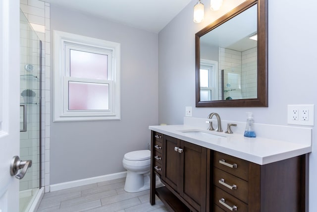 full bath featuring toilet, tiled shower, vanity, wood finish floors, and baseboards