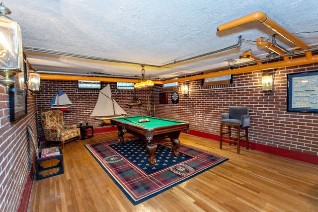 736 Chicago Blvd, Detroit, MI 48202 - game room featuring a textured ceiling, hardwood / wood-style floors, billiards table, brick wall, and baseboards