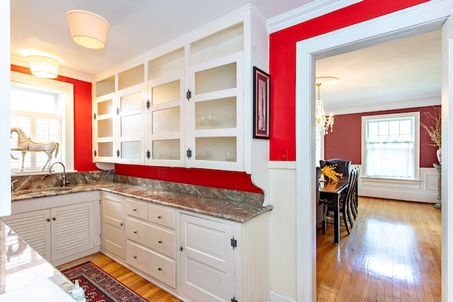 736 Chicago Blvd, Detroit, MI 48202 - kitchen with crown molding, a sink, light wood-style floors, white cabinetry, and glass insert cabinets