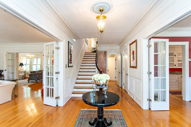 736 Chicago Blvd, Detroit, MI 48202 - foyer entrance with french doors, a chandelier, stairs, light wood-style flooring, and ornamental molding