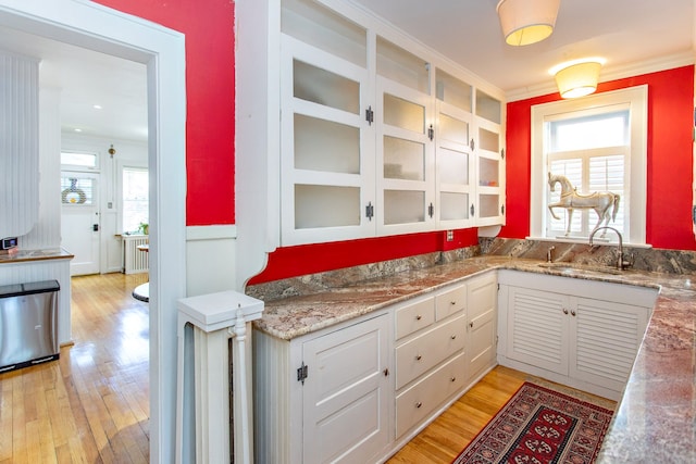 736 Chicago Blvd, Detroit, MI 48202 - kitchen featuring a sink, light wood-style floors, white cabinets, glass insert cabinets, and ornamental molding