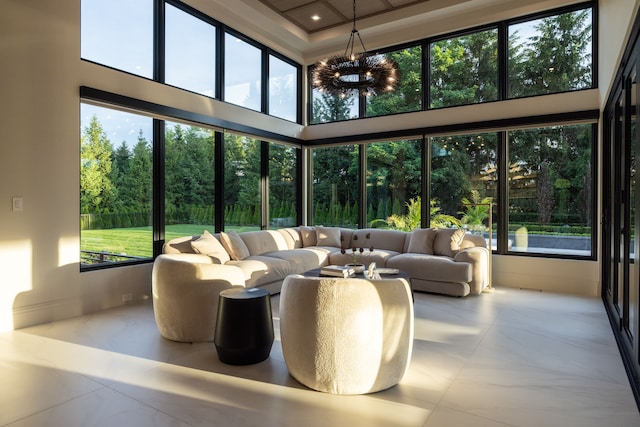sunroom with a high ceiling, a chandelier, healthy amount of natural light, and tile patterned floors