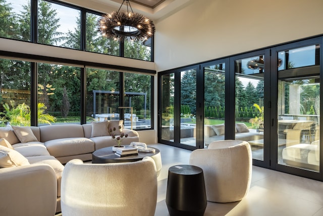 tiled living room featuring healthy amount of natural light, a chandelier, and a towering ceiling