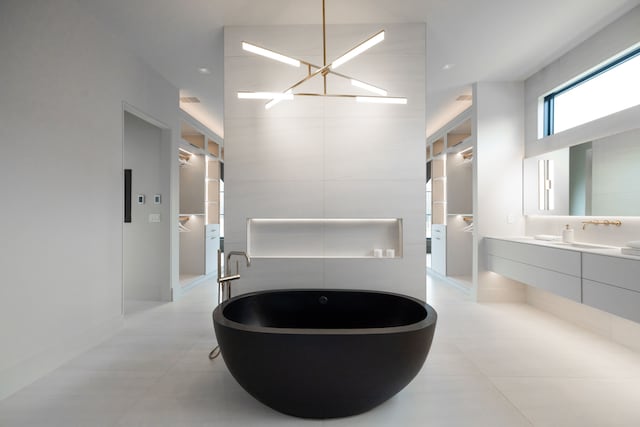 bathroom with a soaking tub, a chandelier, and vanity