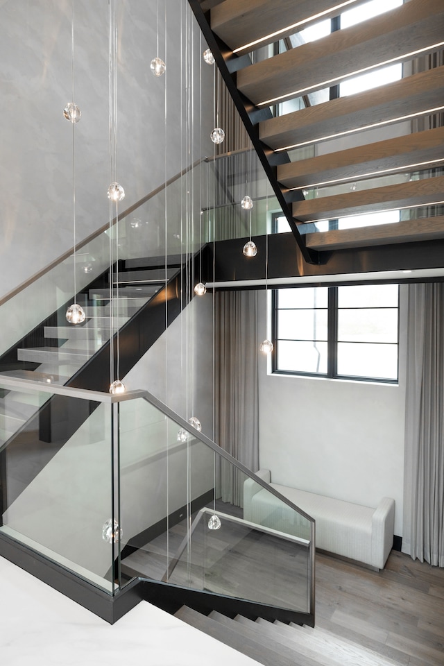 stairway featuring wood finished floors and a towering ceiling