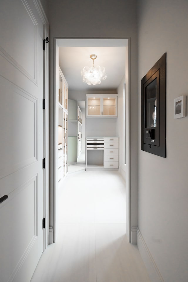 corridor featuring a chandelier and baseboards