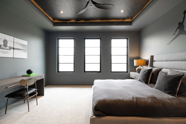 carpeted bedroom featuring a raised ceiling, multiple windows, and crown molding