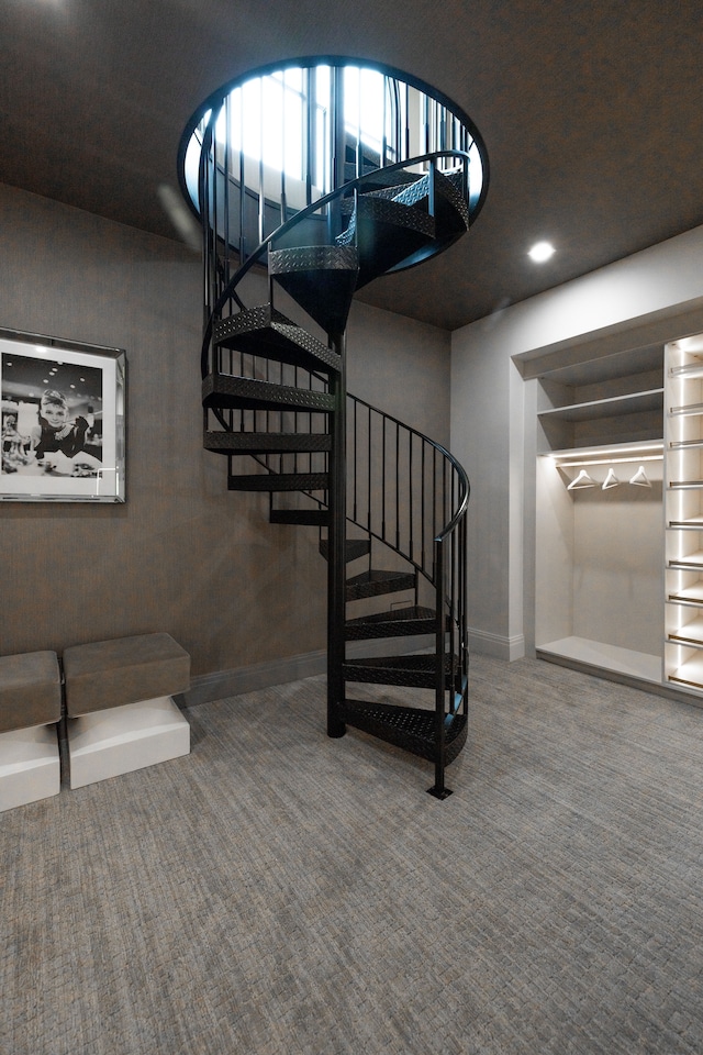 stairway featuring baseboards and carpet flooring