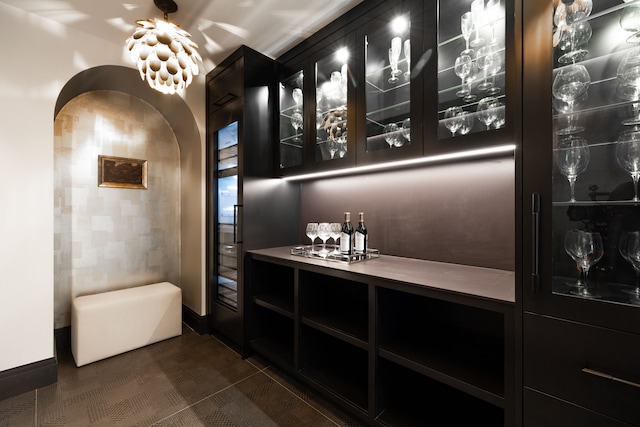 indoor dry bar featuring arched walkways and baseboards
