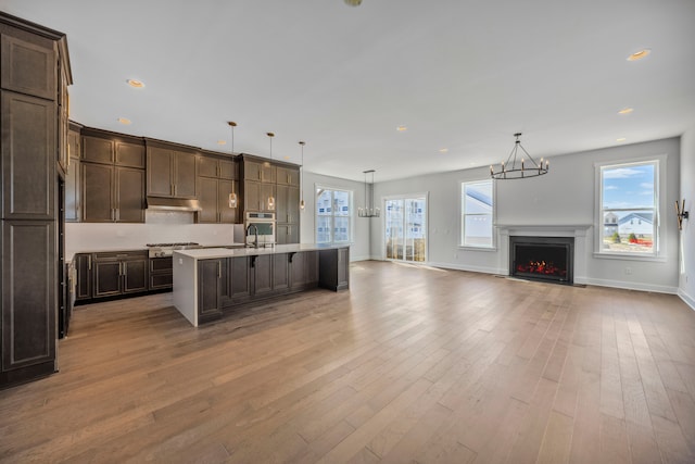 5636 Suffolk Ct, West Bloomfield, MI 48322 - kitchen featuring under cabinet range hood, open floor plan, dark brown cabinets, a chandelier, and recessed lighting