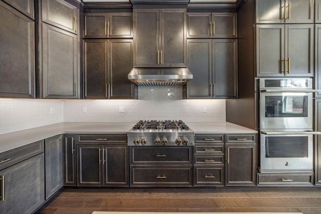 5636 Suffolk Ct, West Bloomfield, MI 48322 - kitchen with stainless steel appliances, light countertops, dark wood-style flooring, under cabinet range hood, and decorative backsplash
