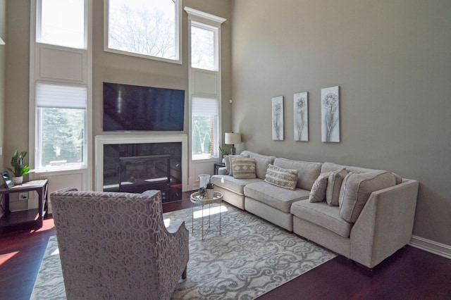 194 W Reed Lk, Commerce Twp, MI 48390 - living area featuring a towering ceiling, wood finished floors, a glass covered fireplace, and baseboards