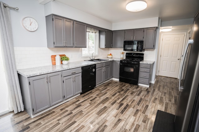 11748 Cloverview Dr, Ravenna, MI 49451 - kitchen with black appliances, a sink, gray cabinets, wood finished floors, and backsplash