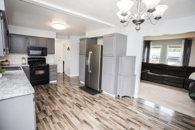 11748 Cloverview Dr, Ravenna, MI 49451 - kitchen featuring black appliances, light countertops, a sink, tasteful backsplash, and a chandelier