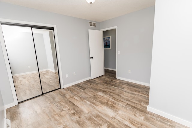 11748 Cloverview Dr, Ravenna, MI 49451 - unfurnished bedroom featuring wood finished floors, a closet, and baseboards