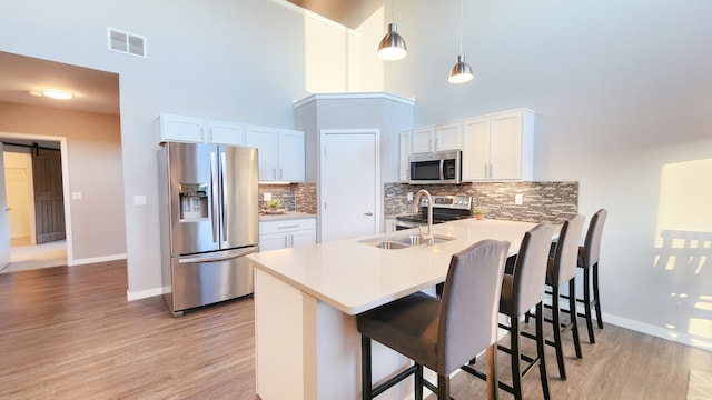 293 N 2nd St, Brighton, MI 48116 - kitchen with stainless steel appliances, a peninsula, light wood-style floors, baseboards, and a towering ceiling