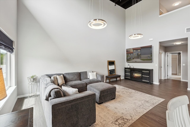 293 N 2nd St, Brighton, MI 48116 - living area with a high ceiling, dark wood-type flooring, baseboards, and a glass covered fireplace