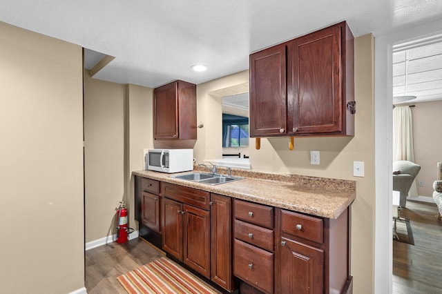 08763 Silver Lake Rd, Grand Junction, MI 49056 - kitchen with white microwave, a sink, wood finished floors, light countertops, and baseboards