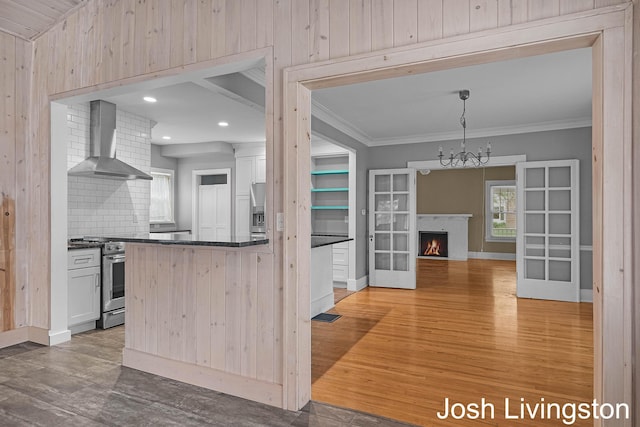 957 Breton Rd SE, Grand Rapids, MI 49506 - kitchen with wall chimney exhaust hood, dark countertops, wood finished floors, a warm lit fireplace, and white cabinets