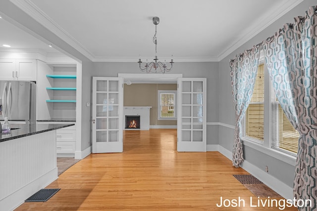 957 Breton Rd SE, Grand Rapids, MI 49506 - unfurnished dining area with light wood-type flooring, french doors, a chandelier, and ornamental molding