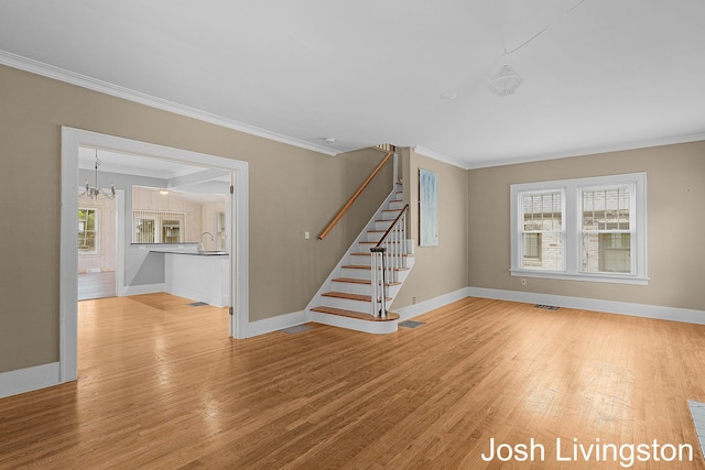 957 Breton Rd SE, Grand Rapids, MI 49506 - unfurnished living room featuring ornamental molding, stairs, baseboards, light wood-style flooring, and a chandelier
