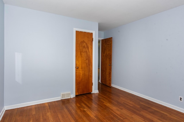 empty room with dark wood-style flooring and baseboards