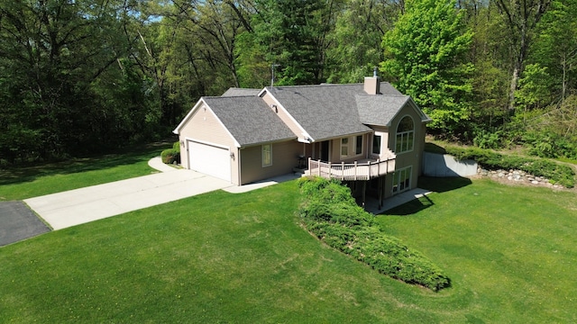 view of front of property with driveway, a chimney, an attached garage, and a front yard