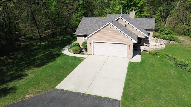 view of front of home with concrete driveway, an attached garage, a wooded view, and a front lawn