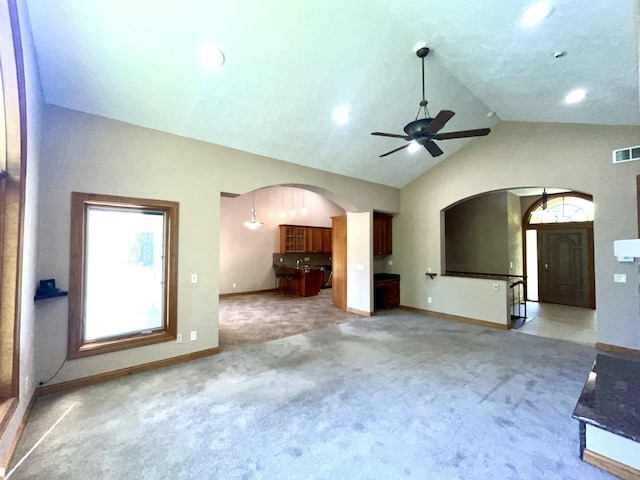 unfurnished living room with arched walkways, light carpet, baseboards, lofted ceiling, and recessed lighting