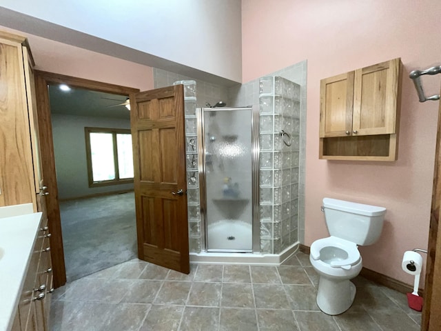 full bathroom with a shower stall, toilet, vanity, a ceiling fan, and baseboards