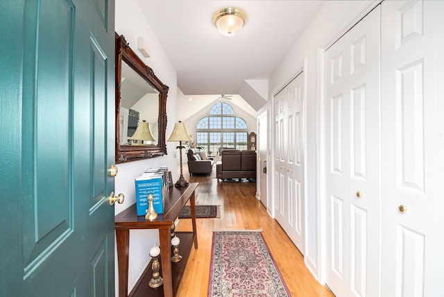 hall featuring light wood-style flooring and vaulted ceiling