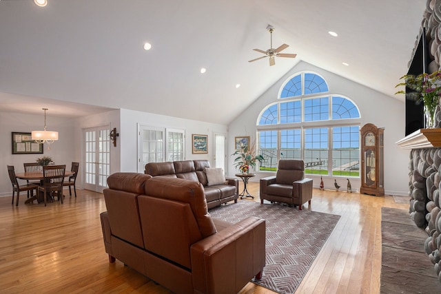 living room featuring a ceiling fan, high vaulted ceiling, and light wood finished floors