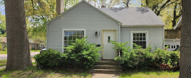 view of front of house with a chimney and roof with shingles
