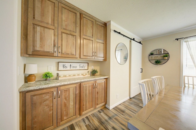 6418 Apple Way, Fenton, MI 48430 - kitchen with a barn door, wood finished floors, light countertops, ornamental molding, and brown cabinetry