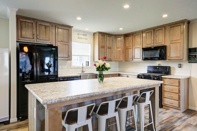 6418 Apple Way, Fenton, MI 48430 - kitchen featuring black appliances, a sink, light wood-style floors, a breakfast bar, and recessed lighting