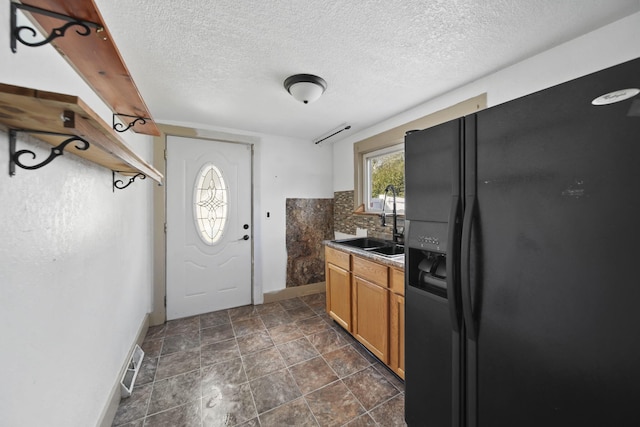 1702 Teneyck St, Jackson, MI 49203 - kitchen featuring black fridge, baseboards, decorative backsplash, a sink, and a textured ceiling