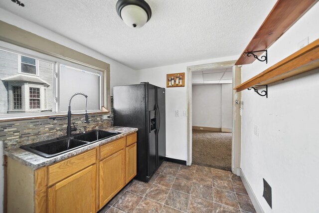 1702 Teneyck St, Jackson, MI 49203 - kitchen featuring black fridge with ice dispenser, a sink, baseboards, backsplash, and a textured ceiling