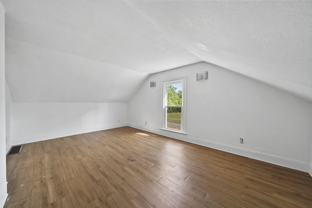 1702 Teneyck St, Jackson, MI 49203 - bonus room with lofted ceiling, wood finished floors, baseboards, and a textured ceiling