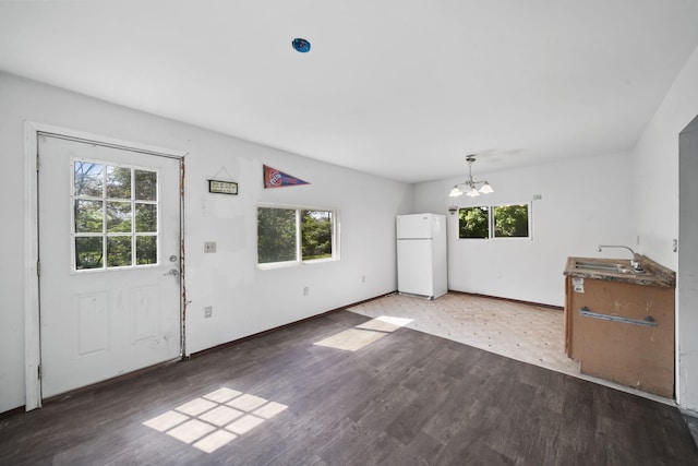 1702 Teneyck St, Jackson, MI 49203 - unfurnished living room featuring a chandelier, a sink, light wood-style flooring, and baseboards