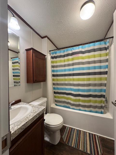 full bath with shower / bath combo, vanity, toilet, wood finished floors, and a textured ceiling