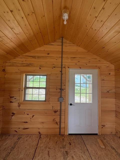 doorway to outside with vaulted ceiling, wood walls, and wood ceiling