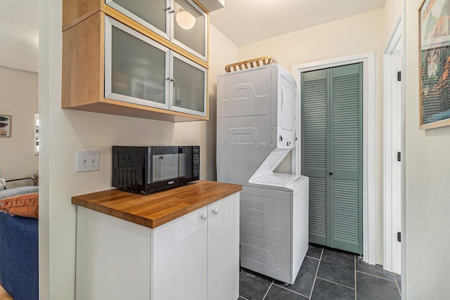 371 4th St, Pentwater, MI 49449 - clothes washing area with stacked washer / drying machine, cabinet space, and dark tile patterned flooring