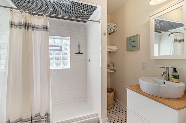 371 4th St, Pentwater, MI 49449 - bathroom featuring a tile shower, vanity, and baseboards
