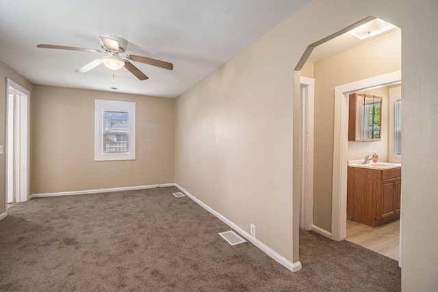 2335 Holmes Rd, Ypsilanti, MI 48198 - unfurnished room with light carpet, arched walkways, a sink, a ceiling fan, and baseboards