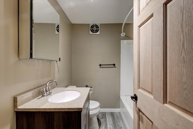 bathroom with toilet, a bathtub, vanity, wood finished floors, and baseboards
