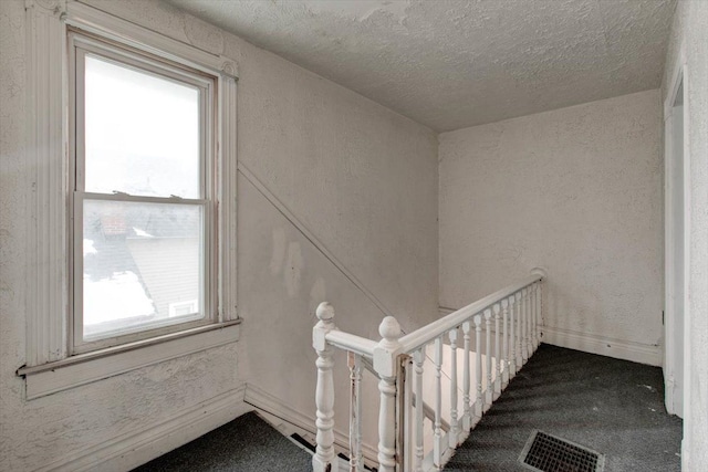 staircase featuring a textured ceiling and carpet