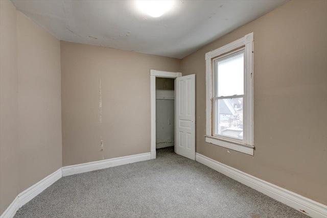unfurnished bedroom featuring carpet, baseboards, and a closet