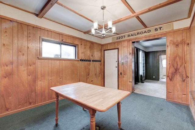 carpeted dining room with a chandelier and wood walls