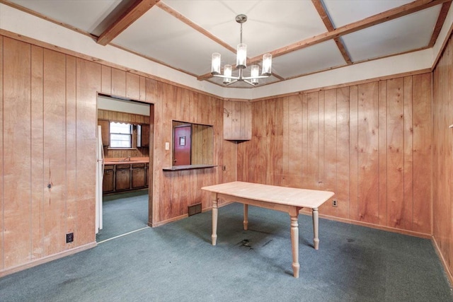 unfurnished office with a chandelier, wood walls, carpet flooring, coffered ceiling, and beam ceiling